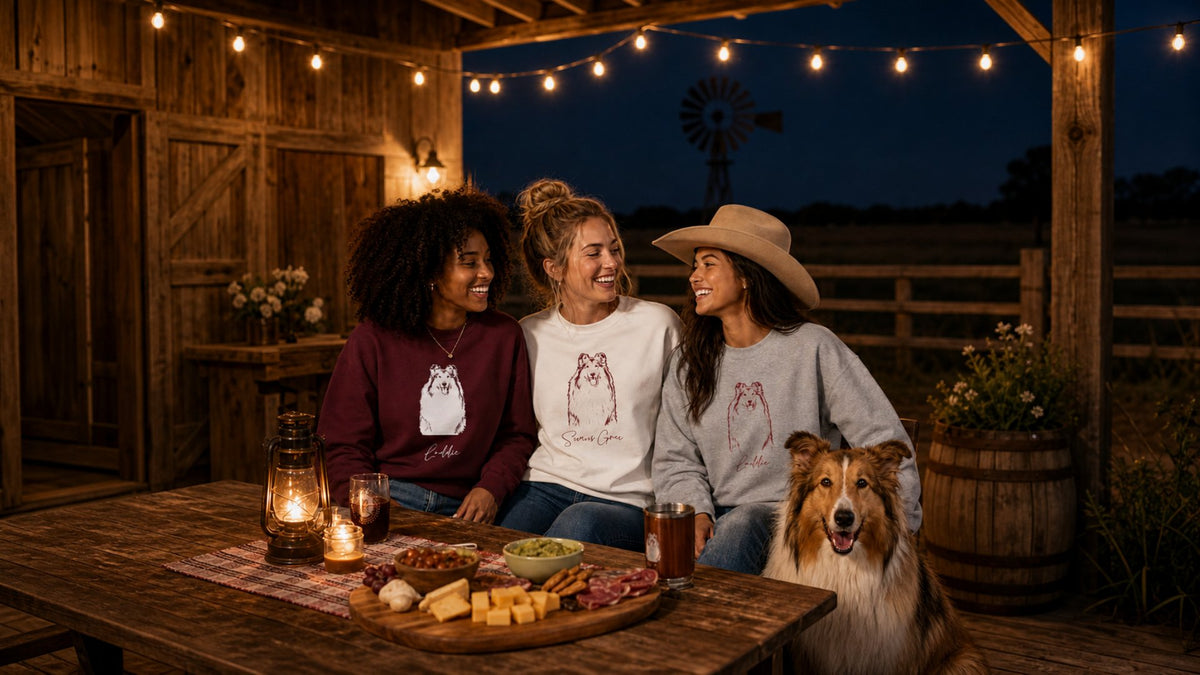 Friends celebrating in custom pet pride sweatshirts with their collie dog in an outdoor barn pavilion with string lights.