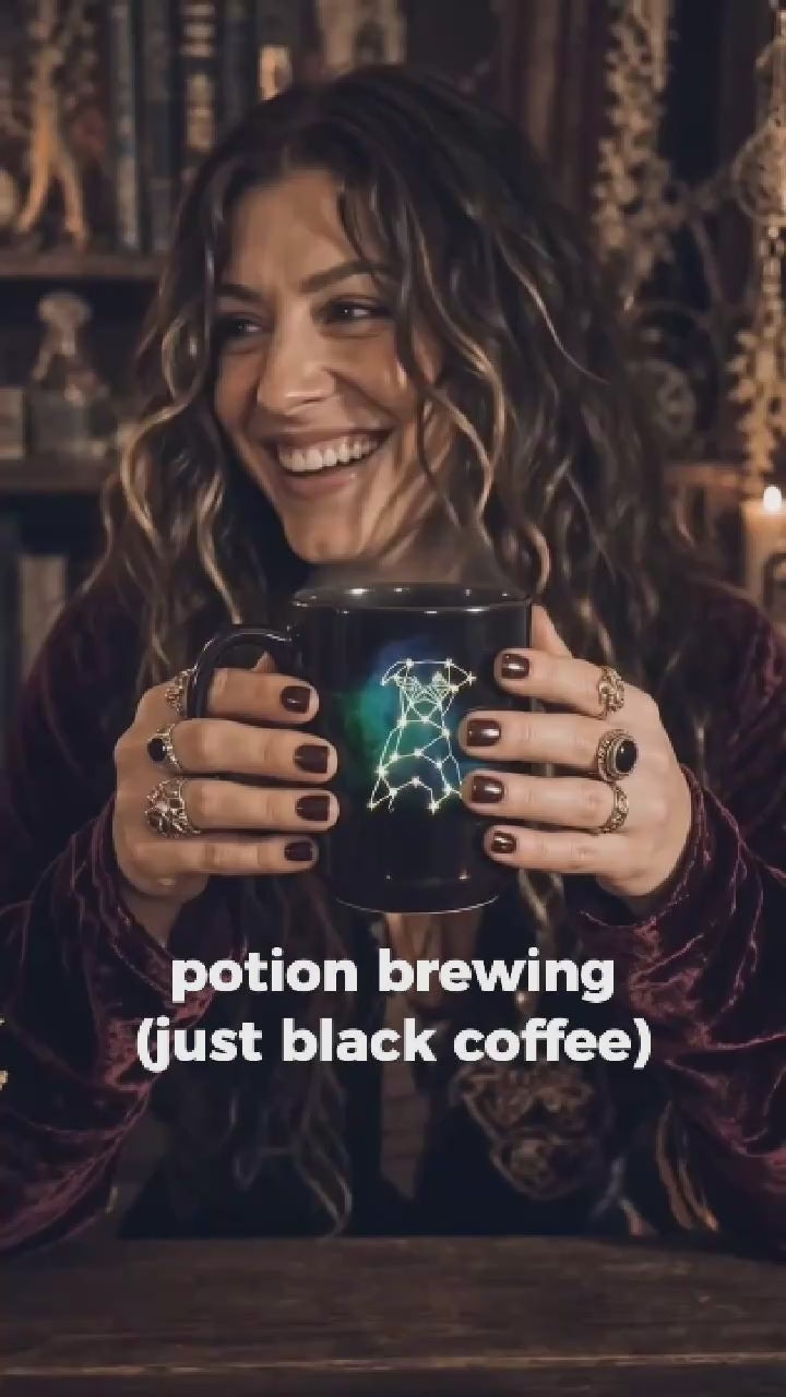 Hands holding a glossy black ceramic mug featuring a custom white line-art dog sketch and celestial stars with steam rising.